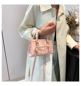 Pink marbled rectangle handbag with gold hardware and shoulder strap on cream coat