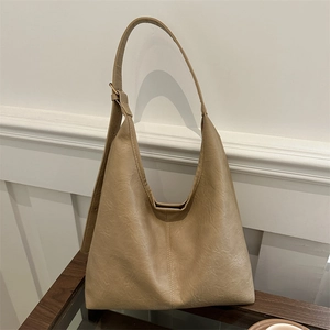 Fashionable khaki leather tote bag with adjustable strap on a minimal wooden table