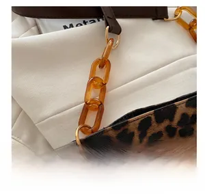Detail of leopard print shoulder bag featuring amber acrylic chain and metal ring connector