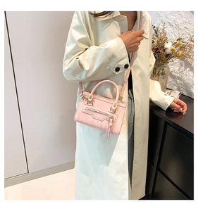 Pink minimalist crossbody bag with top handles and tassel zipper detail shown in lifestyle view
