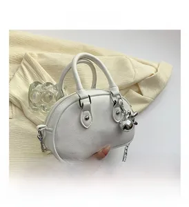 Detail shot of white litchi leather mini handbag with silver chain and metal ball charm
