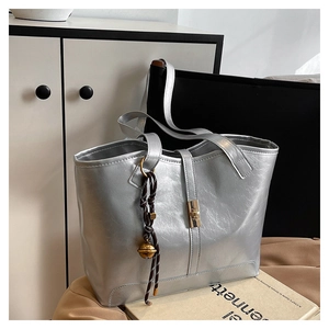 Detail of silver metallic tote bag with brushed texture and gold square lock closure