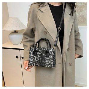 Leopard print crossbody handbag with round handles styled on a beige wool coat