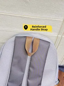Detail view of reinforced handle and breathable mesh shoulder straps on the gray nylon backpack