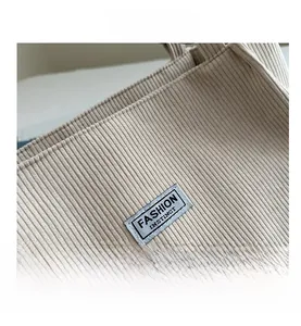 Dettaglio della trama in velluto a coste beige e dell'etichetta tessuta Fashion Instinct