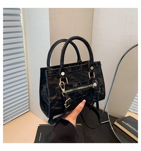 Close-up of black handbag with pleated texture and polished gold hardware accents
