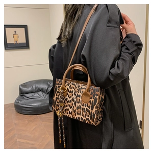 Fashionable leopard print crossbody bag with brown round handles on a black trench coat
