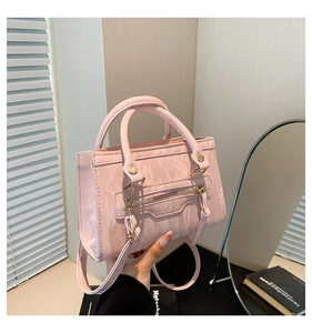 Close-up of pink pleated patent leather handbag with adjustable strap and zip detail