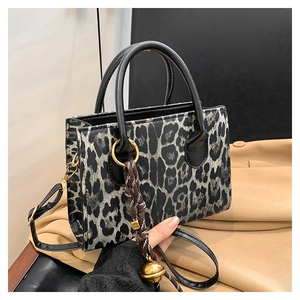 Detail of leopard print tote bag with gold ring handle and decorative bell charm
