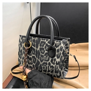Close-up of leopard print handbag with golden ring and woven ball charm accessory