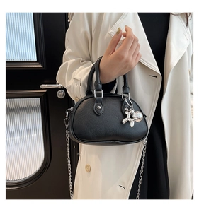 Detail of black pebbled leather circular handbag with silver balloon dog pendant and chain