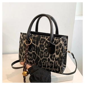 Detail of leopard print tote bag with round handles and decorative golden charm