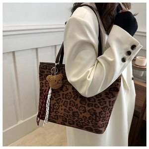 Detail of leopard print tote bag with plush bear charm and brown leather straps