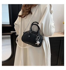 Detail of black pebbled leather mini Boston bag with silver chain and bear charm on model