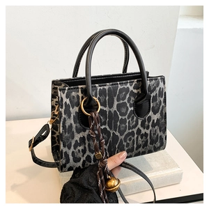 Detailed close-up of leopard print handbag featuring gold hardware and a tassel charm
