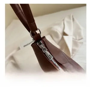 Detailed close-up of smooth silver metal zipper on brown pebble leather tote bag