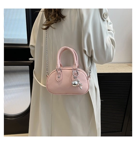 Close-up of pink round handbag with silver metal dog charm and litchi grain leather