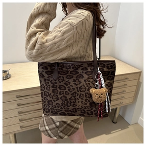 Detail of vintage leopard print tote bag with brown leather strap and plush bear charm