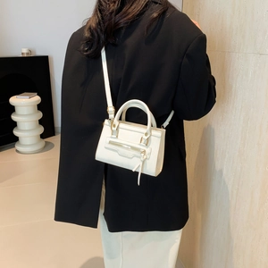 Minimalist cream white leather crossbody bag with dual handles and metal zipper detail
