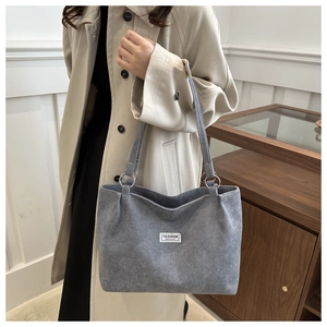 Dettaglio della borsa tote in velluto a coste blu-grigio con trama morbida e patch