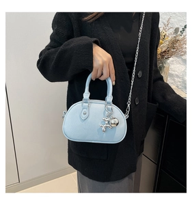 Detail of light blue textured leather mini shell bag with a silver balloon dog charm