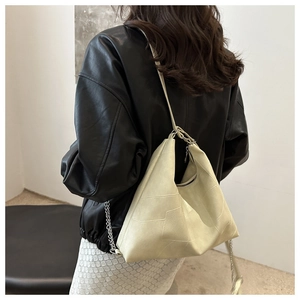 Detailed patchwork leather texture and metal chain strap of a beige tote bag on model