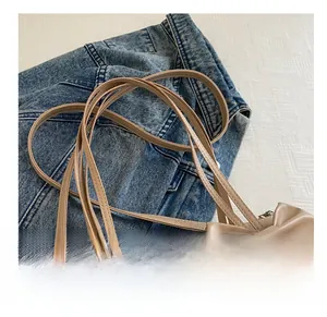 Detail der beigen Ledertasche mit eleganter großer Schleife und Mehrfachriemen-Design