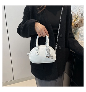 Close-up of white round handbag with lychee texture and silver balloon dog charm