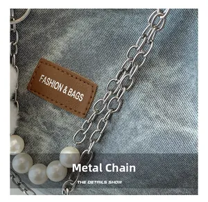 Detail of grey washed denim tote with silver chain, pearl charm and leather patch