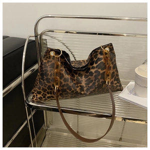Detail view of leopard print handbag with amber acrylic chain on a glass shelf