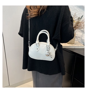 Close-up of a white lychee leather mini bowling bag with silver chain and sphere charm