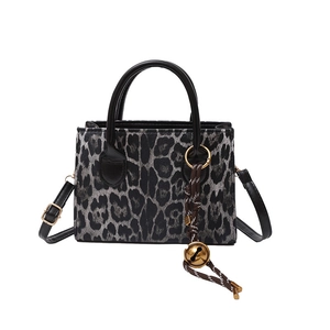 Chic leopard print crossbody handbag with black handles and vintage bell charm
