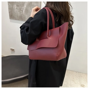 Dettaglio della borsa tote in pelle bordeaux con tracolla indossata da una modella