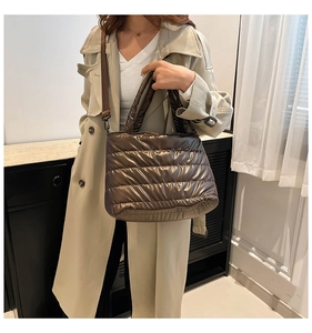Detailansicht der gesteppten Puffer-Tasche in glänzendem Bronze mit breitem Griff