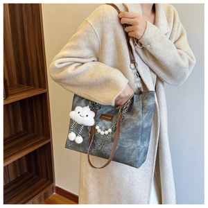 Detail view of gray canvas tote with leather straps, chains, pearls, and cloud charm