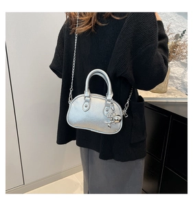 Detail of silver metallic mini bag with balloon dog charm and metal chain strap