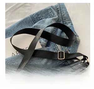 Detail of black quilted nylon bag showing the wide adjustable strap with gold metal buckle