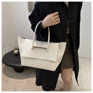 Dettaglio di una grande borsa tote in pelle crema portata da una modella in stile minimal
