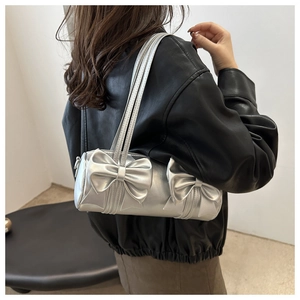 Detailansicht der silbernen Zylindertasche mit Schleifen und doppelten Schultergurten