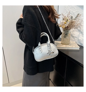 Detail of silver round handbag with lychee texture and metallic bear charm