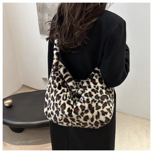 Détail d'un grand sac à bandoulière en peluche imprimé léopard porté par un mannequin chic
