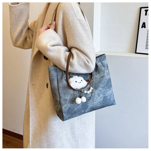 Detail of grey tote bag with metallic chain, large pearl charm and cloud pendant