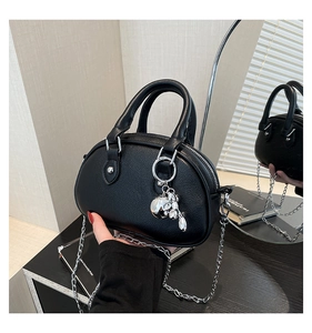 Detail of black shell-shaped handbag with lychee texture and silver rabbit charm