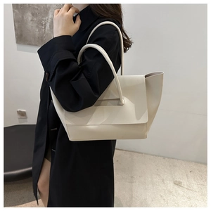 Minimalist cream tote bag styled on black coat in a modern studio setting for daily commute