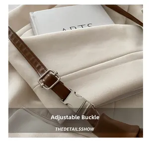 Detailed close-up of brown leather shoulder strap with metallic adjustable buckle