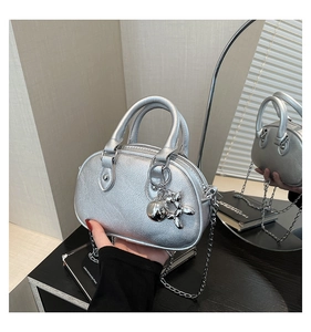Detail of silver metallic textured handbag featuring balloon dog charm and chain strap