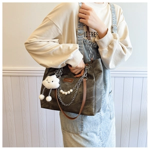 Close-up of dark grey canvas tote with white pearl chain and cloud plush charm