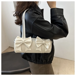 Detailansicht der weißen zylindrischen Schultertasche mit großen Schleifen und Glanzeffekt