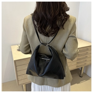 Detail view of black geometric patchwork leather tote bag carried on woman shoulder