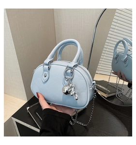 Detail view of light blue round boston bag with silver rabbit pendant and chain